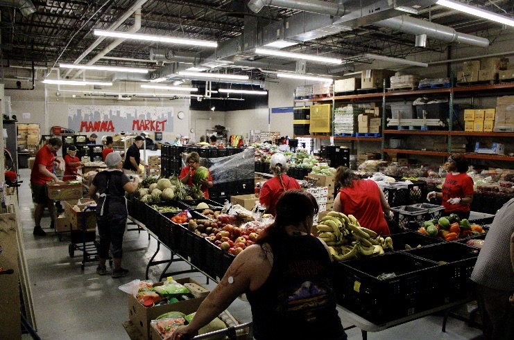 Warehouse with tables full of produce and volunteers